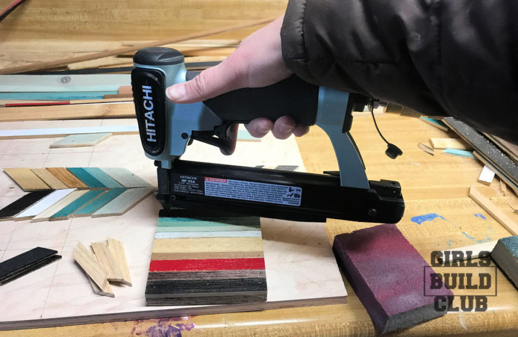 Here I am nailing down the strips of the wood mosaic.  First I put a tiny bit of wood glue on the back of each piece of wood.  Click through for the full diy tutorial on how to make your first wood mosaic.